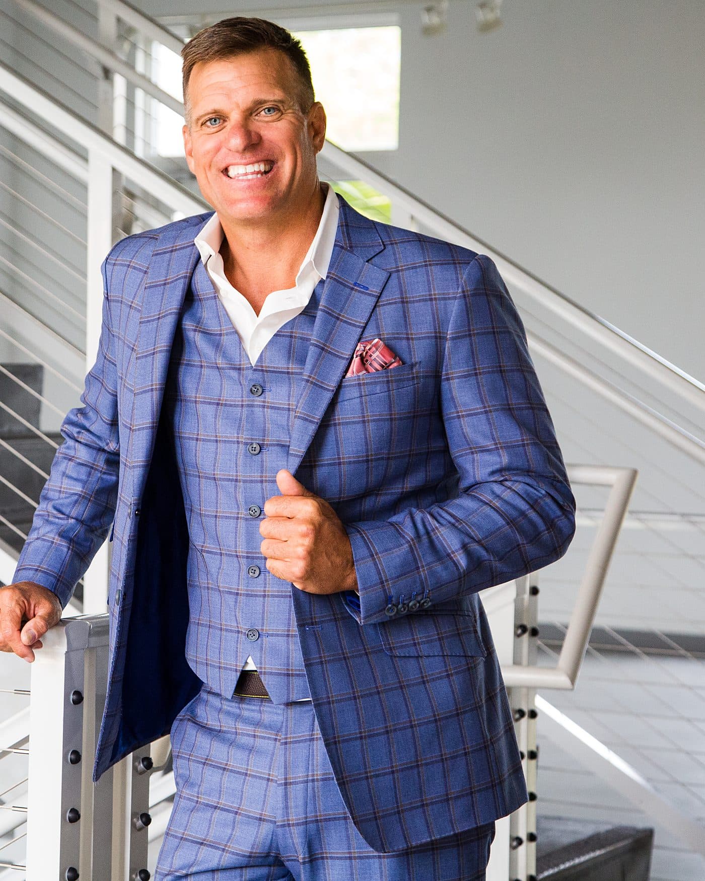 Dave VanHoose on a staircase in a three-piece suit, one hand on the rail